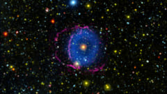 青いリング状の星雲とその周囲を縁取るような細い赤色の帯が見える。これは紫外線波長の光で肉眼では見えない。
