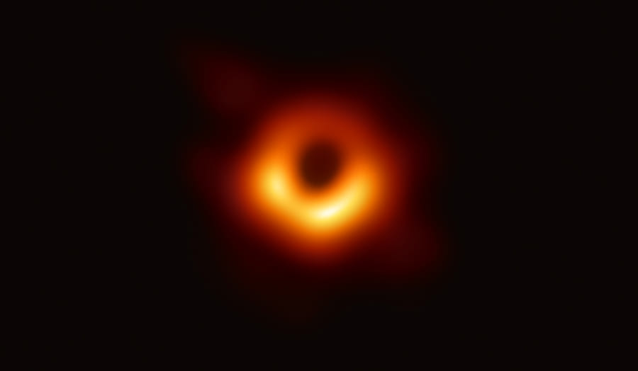2019年に公開されたM87銀河の中心にあるブラックホールシャドウの画像。ブラックホールの強い重力場に影響を受けて渦巻いている熱いガスが明るく輝いている。