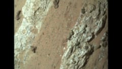 白い鉱脈の間に赤茶色の岩石がある、その上にはヒョウ柄のような斑点が見られる
